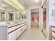 Bright bathroom featuring dual sinks with white cabinets and detailed mirrors with floral wallpaper at 702 Plumbrook Rd, Sun City Center, FL 33573