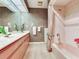 Bathroom showcasing an extended mirror above the countertop and light pink shower and tub at 702 Plumbrook Rd, Sun City Center, FL 33573