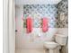 Bathroom featuring a floral wallpaper with a toilet with white tile and pink towels at 702 Plumbrook Rd, Sun City Center, FL 33573