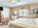 Bedroom view showcasing a white dresser, rocking chair, with a floral-patterned comforter on the bed at 702 Plumbrook Rd, Sun City Center, FL 33573