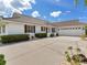 Charming exterior featuring a wide driveway, lush landscaping, and a two-car garage at 702 Plumbrook Rd, Sun City Center, FL 33573