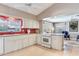 Bright kitchen with white cabinets and appliances, with view into sitting area at 702 Plumbrook Rd, Sun City Center, FL 33573