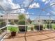 Screened-in lanai with views of the yard and neighboring buildings under a bright blue sky at 702 Plumbrook Rd, Sun City Center, FL 33573