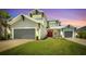 Charming two-story home featuring a well-manicured lawn, two-car garage, and inviting red front door at twilight at 7201 Talamore Dr, Wesley Chapel, FL 33545