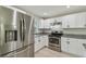 Well-lit kitchen features stainless steel appliances, white cabinets, and granite countertops at 7308 Avonwood St, Tampa, FL 33625