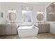 Luxurious bathroom featuring a freestanding tub, dual vanities, and elegant lighting fixtures at 7520 Paradiso Dr, Apollo Beach, FL 33572