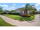 Well-maintained front yard with lush green grass, mature trees, and colorful flowerbeds surrounding a single-Gathering home at 7520 Paradiso Dr, Apollo Beach, FL 33572