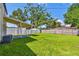 Large backyard with a covered patio, wooden fence, and mature trees offering ample space for outdoor enjoyment at 7806 N Matanzas Ave, Tampa, FL 33614