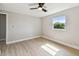 A vacant bedroom featuring a window, neutral paint, ceiling fan, and light wood-look flooring at 7806 N Matanzas Ave, Tampa, FL 33614