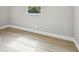 A vacant bedroom featuring a window, neutral paint, and light wood-look flooring at 7806 N Matanzas Ave, Tampa, FL 33614