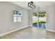 Open living room with laminate floors, modern light fixture, and sliding glass door to the backyard at 7806 N Matanzas Ave, Tampa, FL 33614