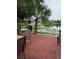 This backyard has a brick paver patio overlooking a serene lake, with a large palm tree and grill at 8718 Lindenhurst Pl, Tampa, FL 33634