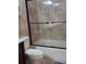 This renovated bathroom offers a tub with shower and updated sliding glass doors at 8718 Lindenhurst Pl, Tampa, FL 33634