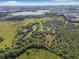 Expansive aerial view of a charming property surrounded by lush greenery and a picturesque lake in the distance at 8843 Kenton Rd, Wesley Chapel, FL 33545