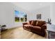 Bright living room with hardwood floors and a brown leather sofa in front of a large window at 8843 Kenton Rd, Wesley Chapel, FL 33545