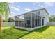 Exterior view of the backyard featuring an enclosed screened patio, wooden deck and green grass at 915 Windton Oak Dr, Ruskin, FL 33570