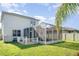 Exterior view of the backyard with an enclosed screened patio, wooden deck and green grass at 915 Windton Oak Dr, Ruskin, FL 33570