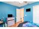Bedroom showcasing vibrant blue walls, hardwood flooring, and natural light from the entryway at 915 Windton Oak Dr, Ruskin, FL 33570