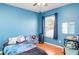 Bright blue bedroom with a window, small chair, and a bed with galaxy patterned blanket at 915 Windton Oak Dr, Ruskin, FL 33570