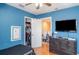 Bright blue bedroom featuring an open closet, TV, and a large dresser with hardwood floors at 915 Windton Oak Dr, Ruskin, FL 33570