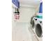 Bright laundry room featuring white tile floors, washer, dryer, and blue cabinets at 945 College Hill Dr, Clearwater, FL 33765