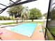 Backyard pool area features a screened-in enclosure, patio, a table and chairs, and a well manicured lawn at 945 College Hill Dr, Clearwater, FL 33765