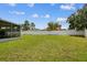 Well-kept backyard featuring a green lawn, a screened-in patio, and surrounded by a white fence at 1032 Jacob Way, Odessa, FL 33556