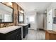 Bathroom featuring dual vanities, modern lighting, a laundry closet, and access to a tiled shower; spacious design at 1032 Jacob Way, Odessa, FL 33556