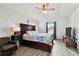 Bright main bedroom with a king bed, ceiling fan, wood-look floors, and a comfortable chair; window view at 1032 Jacob Way, Odessa, FL 33556