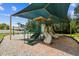 This green shaded playground features a playset with slides and covered roofs on a wood chip surface at 1032 Jacob Way, Odessa, FL 33556