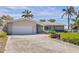 Charming single-story home with a brick driveway, lush landscaping, and a two-car garage at 11055 7Th E St, Treasure Island, FL 33706