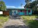 A colorful one-story home with a covered carport with unkempt front lawn at 1504 Stevensons Dr, Clearwater, FL 33755