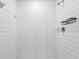 White tiled shower with modern fixtures and convenient storage shelf at 17482 Nectar Flume Dr, Land O Lakes, FL 34638