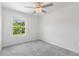 Bright bedroom with carpet, ceiling fan, and a view of lush greenery through the window at 17482 Nectar Flume Dr, Land O Lakes, FL 34638
