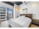 Bright bedroom featuring a modern platform bed, exposed ceiling beams, and a large window with city views at 175 2Nd St S # P-2, St Petersburg, FL 33701
