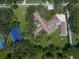 Aerial view of a residence with a tennis court adjacent to a lawn surrounded by trees at 1835 Alicia Way, Clearwater, FL 33764