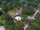Aerial view of a property with an outlined border, showcasing the house, tennis court, and mature trees at 1835 Alicia Way, Clearwater, FL 33764