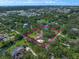 Aerial view of a property with a bordered boundary, tennis court, trees, and nearby cityscape at 1835 Alicia Way, Clearwater, FL 33764