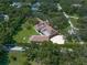 Expansive estate featuring a beautiful brown roof, surrounded by lush greenery and a private tennis court at 1835 Alicia Way, Clearwater, FL 33764
