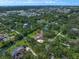 Aerial view of a property surrounded by lush greenery, including a tennis court and mature trees at 1835 Alicia Way, Clearwater, FL 33764