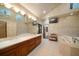 Large bathroom featuring a double sink vanity, jacuzzi tub and a small TV at 1835 Alicia Way, Clearwater, FL 33764