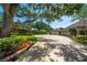 Spacious driveway leading to a well-maintained home with lush landscaping and mature trees providing ample shade at 1835 Alicia Way, Clearwater, FL 33764