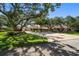Well-manicured lawn with mature trees and a circular driveway leading to a spacious single-story home at 1835 Alicia Way, Clearwater, FL 33764