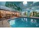 Indoor pool area featuring unique artwork, a connecting kitchen, and natural light at 1835 Alicia Way, Clearwater, FL 33764