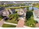Aerial view of a home with manicured landscaping and brick driveway near a pond and other homes in a residential neighborhood at 19656 Long Lake Ranch Blvd, Lutz, FL 33558