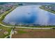 Aerial view showcasing a serene lake surrounded by community walking path and manicured lawn at 19656 Long Lake Ranch Blvd, Lutz, FL 33558