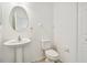 Clean half bathroom with pedestal sink, oval mirror and a white toilet at 19656 Long Lake Ranch Blvd, Lutz, FL 33558