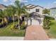 Two-story home boasting a brick driveway, manicured lawn, and mature landscaping showcasing excellent curb appeal at 19656 Long Lake Ranch Blvd, Lutz, FL 33558