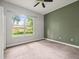 Cozy bedroom showcasing carpeted floors, a large window with outdoor view, and painted accent wall at 2409 Heather Manor Ln, Lutz, FL 33549