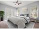 Bright bedroom featuring a ceiling fan, plantation shutters, and a decorative rug at 2409 Heather Manor Ln, Lutz, FL 33549